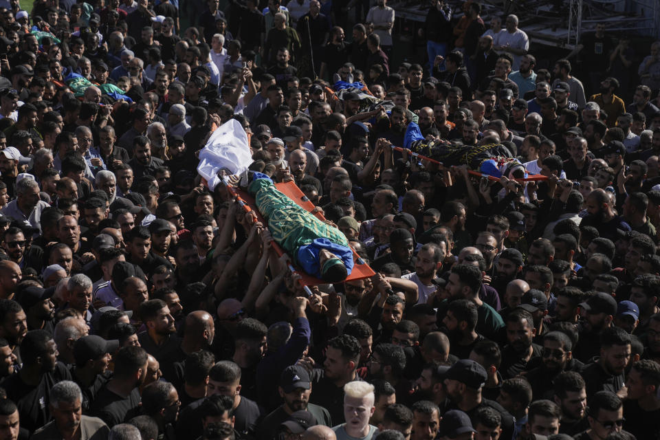 Mourners carry the bodies of Palestinians, some are draped in the Hamas and Islamic Jihad militant group flags during their funeral in the Nur Shams refugee camp, near the West Bank town of Tulkarem, Sunday, April 21, 2024. The Palestinian Red Crescent rescue service said 14 bodies have been recovered from the Nur Shams urban refugee camp since an Israeli military operation began in the area Thursday night. The Islamic Jihad militant group confirmed the deaths of three members. Another killed was a 15-year-old boy. The Israeli army said its forces killed 10 militants in the camp and surrounding areas while eight suspects were arrested. (AP Photo/Majdi Mohammed)