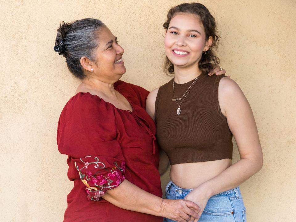Nalleli Cobo and her mother embrace smiling in front of beige wall