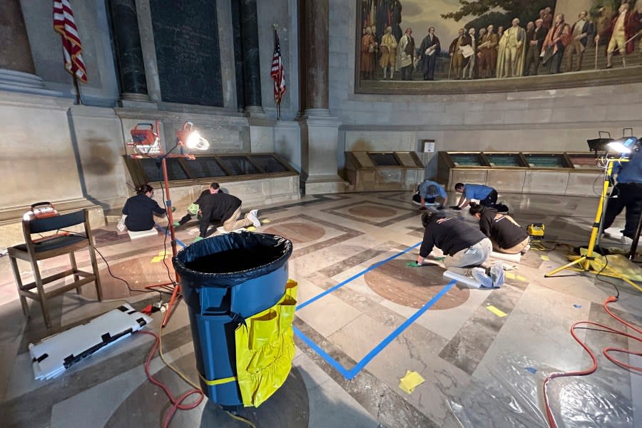 A crew of workers cleans the National Archives Rotunda in Washington, Feb. 14, 2024. The National Archives building and galleries were evacuated after two protesters dumped powder on the protective casing around the U.S. Constitution. (Ellis Brachman/National Archives via AP)