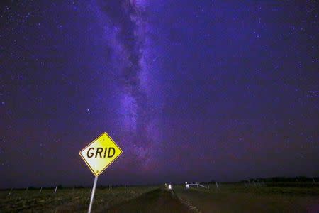 A cattle-grid sign stands on the road with the Milky Way and stars in the background, on the outskirts of Stonehenge in Queensland, Australia, August 12, 2017. REUTERS/David Gray