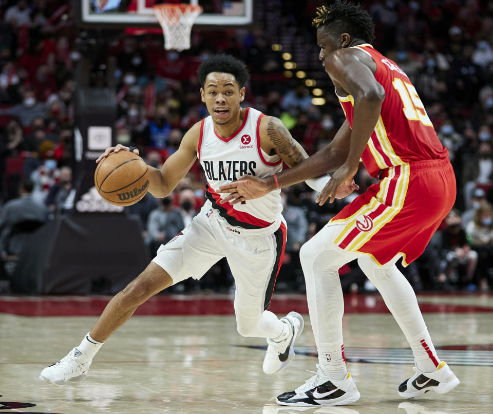 Portland Trail Blazers guard Anfernee Simons, left, dribbles around Atlanta Hawks center Clint Capela during the second half of an NBA basketball game in Portland, Ore., Monday, Jan. 3, 2022. (AP Photo/Craig Mitchelldyer)