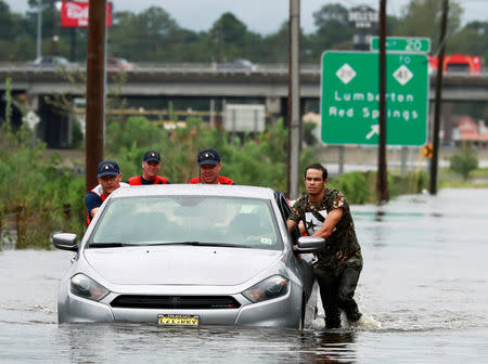 Members of the Coast Guard help a stranded motorist in the flood waters caused by Hurricane Florence in Lumberton, North Carolina, U.S. September 16, 2018. REUTERS/Jason Miczek