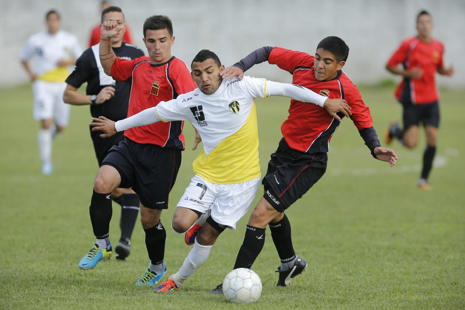 Marcelo Benitez, center, of the "Papa Francisco," or Pope Francis team, vies for the ball between Trefules' David Vallejos, right, and Juan Manuel Pianetti in Lujan, Argentina, Saturday, April 12, 2014. The match was the debut for the semi-professional Pope Francis team, which wore uniforms with the colors of the Vatican flag. (AP Photo/Victor R. Caivano)