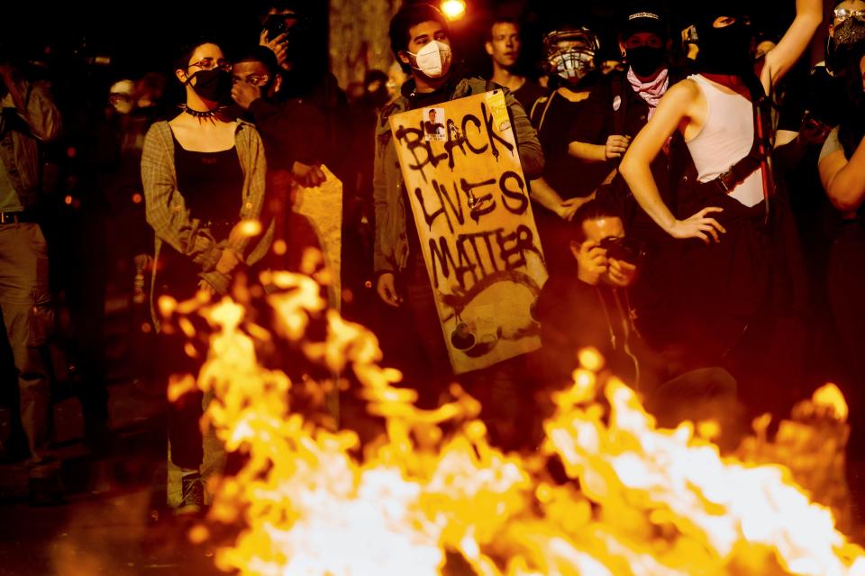 Black Lives Matter protester Jorge Mendoza holds a sign while rallying at the Mark O. Hatfield United States Courthouse on Saturday, Aug. 1, 2020, in Portland, Ore.