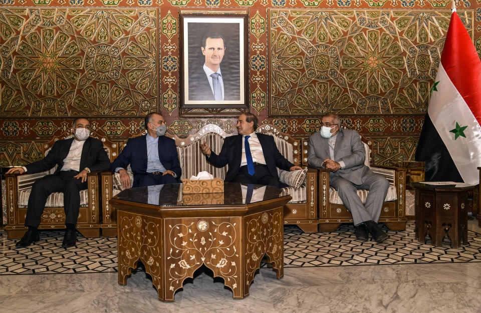 In this photo released by the Syrian official news agency SANA, Syria's Foreign Minister Faisal Mekdad, second right, receives Iran's new Foreign Minister Hossein Amir-Abdollahian, second left, in Damascus, Syria, Sunday Aug. 29, 2021. Mekdad said Sunday that the "thunderous defeat" by the United States in Afghanistan will lead to similar defeats for American troops in Syria and other parts of the world. (SANA via AP)