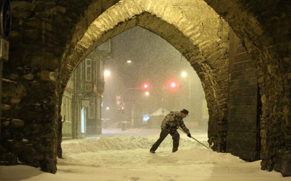 A resident shovels snow under an archway in Wernigerode, Germany, early Sunday morning, Feb. 7, 2021. Low Tristan has caused huge amounts of snow in the Harz mountains, like here in Wernigerode. (Matthias Bein/dpa via AP) - Matthias Bein/DPA