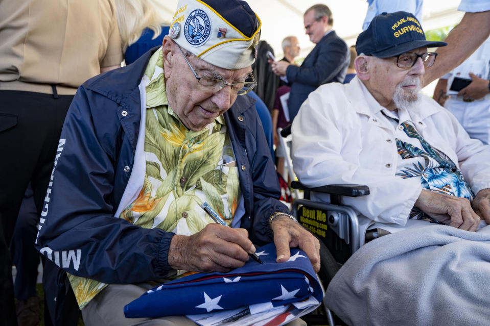 Pearl Harbor survivor Herb Elfring, 101, signs an U.S. flag during the 82nd Pearl Harbor Remembrance Day ceremony on Thursday, Dec. 7, 2023, at Pearl Harbor in Honolulu, Hawaii. (AP Photo/Mengshin Lin)