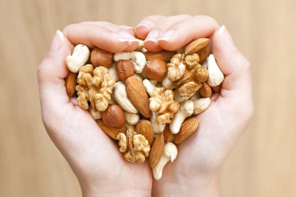 Various nuts in woman hands  forming heart shape