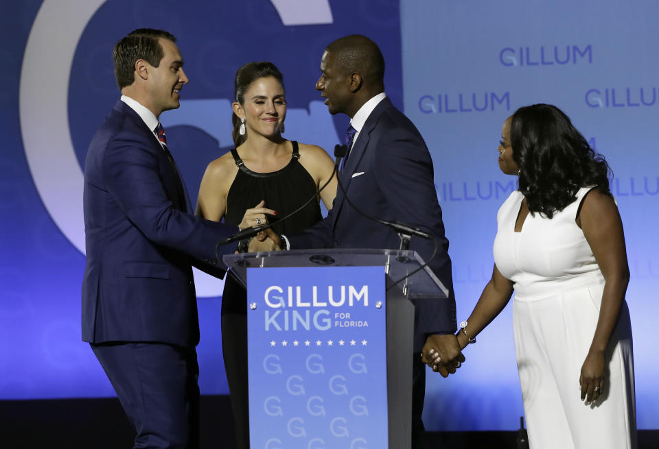 Florida Democratic gubernatorial candidate Andrew Gillum, second from right, shakes hands with running mate Chris King, left, as their wives Kristen King, second from left and R. Jai Gillum, right, look on after Gillum delivered his concession speech Tuesday, Nov. 6, 2018, in Tallahassee, Fla. Gillum lost to Republican former U.S. Rep. Ron DeSantis. (AP Photo/Chris O'Meara)