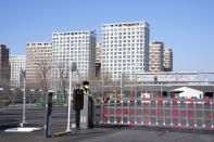 A guard stands near an entrance into the Winter Olympics Village where athletes are expected to stay in Beijing, China, Tuesday, Jan. 25, 2022. Beijing residents are coping with strict local lockdowns and COVID-19 testing requirements as the Chinese capital seeks to prevent a major coronavirus outbreak ahead of the opening of the Winter Olympics in less than two weeks. (AP Photo/Ng Han Guan)