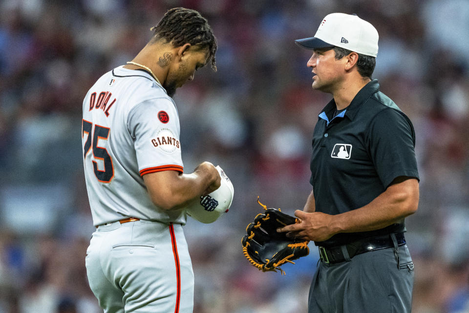 San Francisco Giants pitcher Camilo Doval (75) has his cap and glove checked by umpire Tony Randazzo, right, during the ninth inning of a baseball game against the Atlanta Braves, Thursday, July 4, 2024, in Atlanta. (AP Photo/Jason Allen)