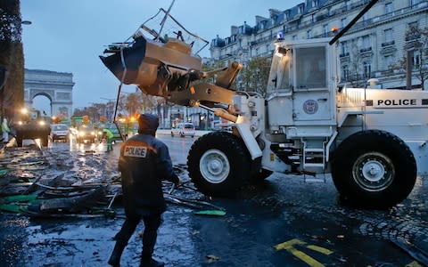 A bulldozer levels the barricade in the aftermath of a protest against the rising of the fuel taxes at the Champs Elysees avenue in Paris - Credit: Michel Euler/AP