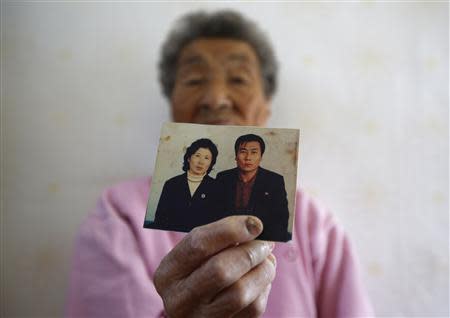 Park Gyu-soon, 88, whose two sons were abducted in 1972 by North Koreans, poses for photographs with a picture of her second son (R) at her house in Nongso village in Geoje, about 470 km (292 miles) southeast of Seoul October 29, 2013. REUTERS/Kim Hong-Ji