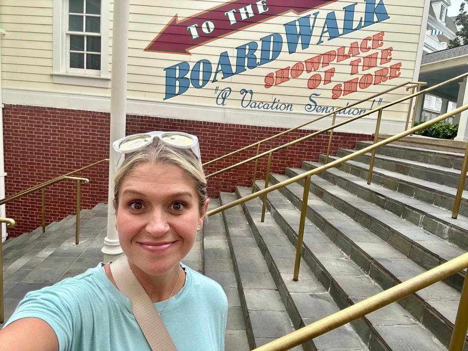 Terri in front of a wall pointing to Disney's BoardWalk