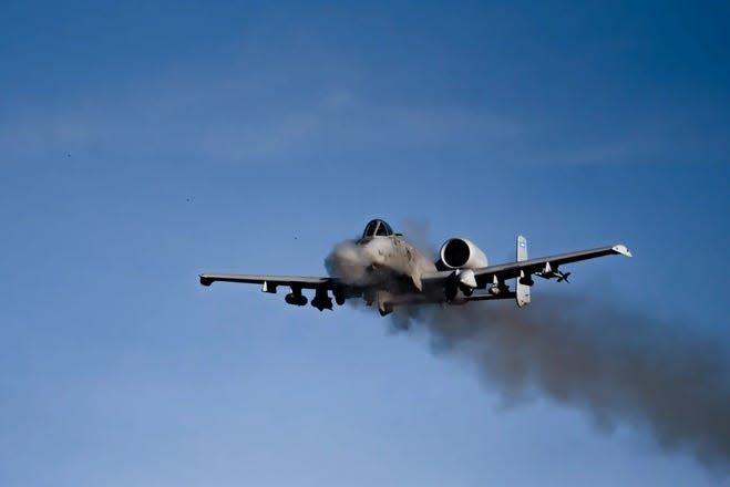 a gray aircraft mid-flight with smoke billowing from behind it