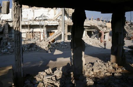 Children walk near damaged buildings in the rebel held besieged city of Douma, in the eastern Damascus suburb of Ghouta, Syria January 7, 2017. Picture taken January 7, 2017. REUTERS/Bassam Khabieh