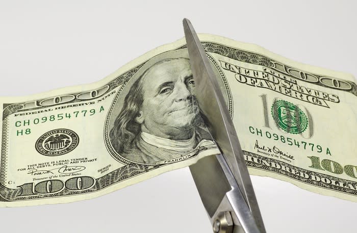 Scissors cutting a $100 bill