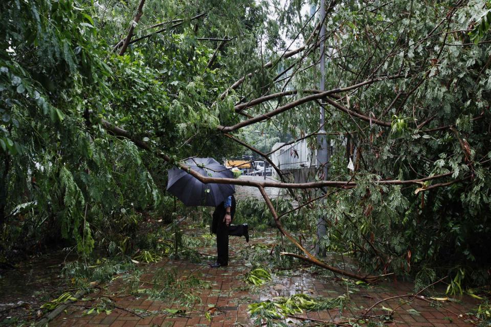 A man walks under fallen branches on a pavement at a residential district after Typhoon Usagi hit Hong Kong