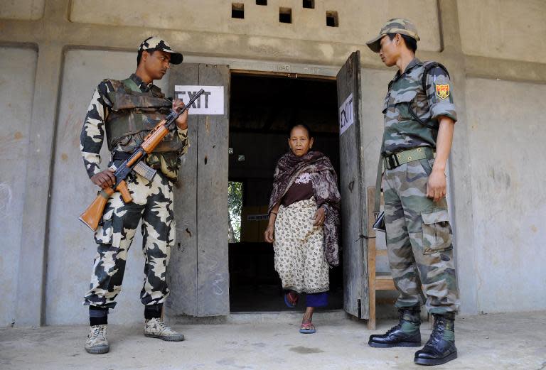 Indian security personnel look on as a voter leaves a polling station after casting her ballot in Kahnmun, some 190 kms from Aizwal, the capital of the northeastern Indian state of Mizoram on April 11, 2014