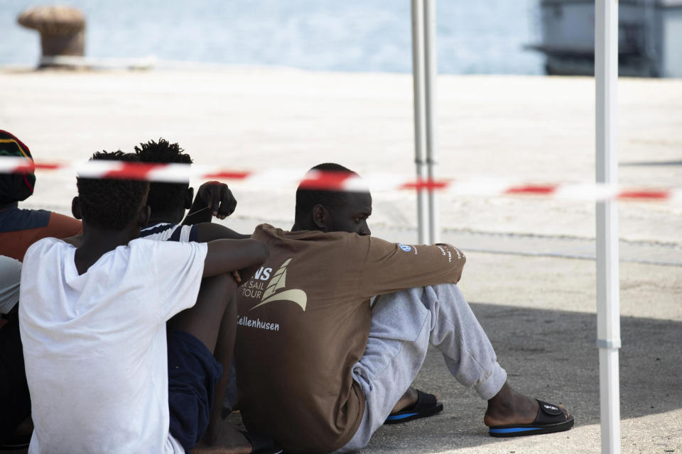 Migrants sits after disembarking from the German rescue boat Eleonore in the port of Pozzallo, Sicily, Southern Italy, Monday, Sept. 2, 2019. Italy’s interior minister is vowing to make the charity boat with some 100 rescued migrants aboard pay dearly for docking in Sicily in defiance of a government ban. (Francesco Ruta/ANSA via AP)