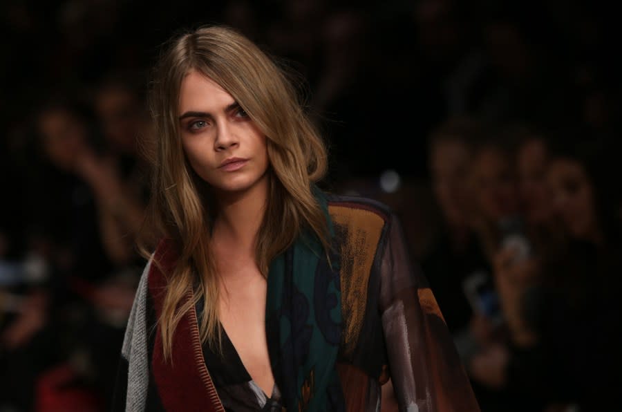 Model Cara Delevingne wears a design created by Burberry Prorsum Womenswear during London Fashion Week Autumn/Winter 2014, at Perks Field, Kensington Palace, in Hyde Park, central London, Monday, Feb. 17, 2014. (Photo by Joel Ryan/Invision/AP)