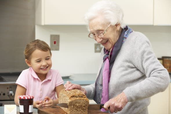 Grandmother and granddaughter preparing food together at home in kitchen