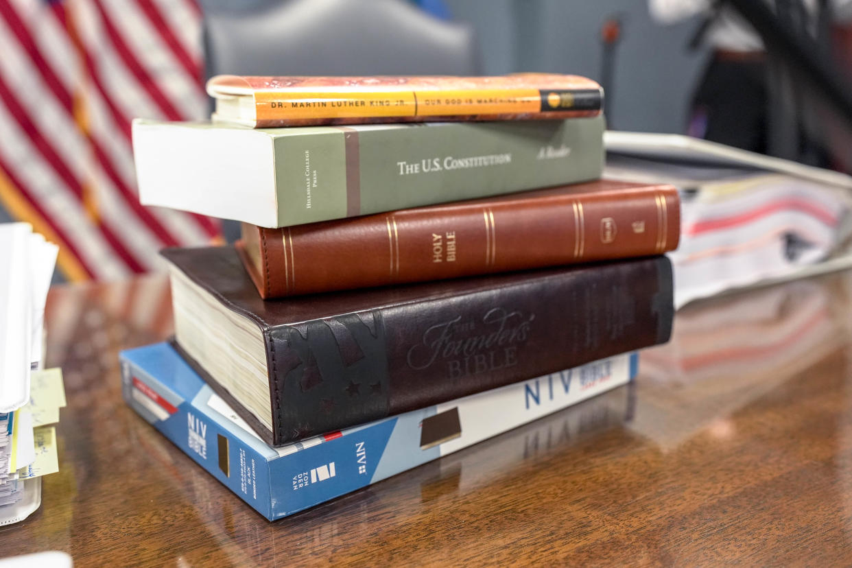 A stack of books, including a bible is placed near State schools Superintendent Ryan Walters’ seat during an Oklahoma school board meeting at the Oklahoma Capitol in Oklahoma City, on Thursday, June 27, 2024.