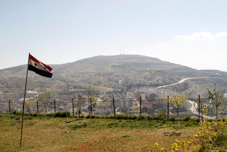 A Syrian national flag flutters as Qasioun mountain is seen in the background from Damascus, Syria April 7, 2017. REUTERS/Omar Sanadiki