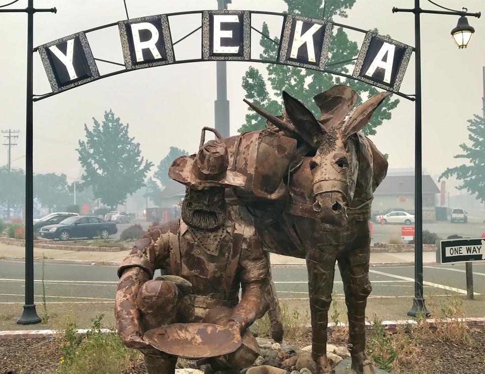 Thick smoke from the McKinney Fire can be seen behind the miner-and-his-mule sculpture in Yreka on Sunday, July 31, 2022. The Yreka lights switched on early in the late afternoon due to the darkened skies.