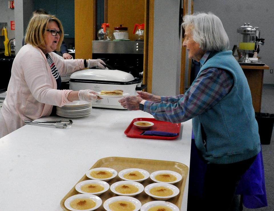 Linda Gossard hands Betty Netzly a plate of pancakes at the Shrove Tuesday meal at the Triinity United Methodist Church in Orrville.