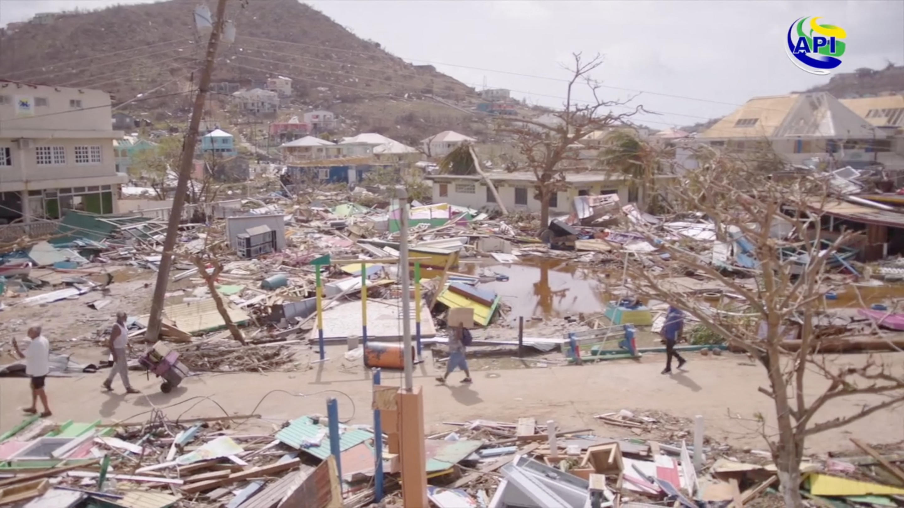 People walk by property damaged by Hurricane Beryl, in Union Island, St. Vincent and the Grenadines.