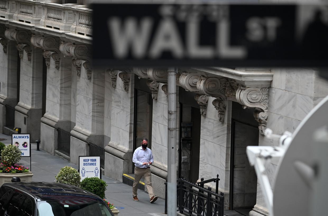 Traders wearing masks arrive before the opening bell at the New York Stock Exchange (NYSE) on May 26, 2020 on Wall Street in New York City. - Global stock markets climbed Monday, buoyed by the prospect of further easing of coronavirus lockdowns despite sharp increases in case rates in some countries such as Brazil. Over the weekend, US President Donald Trump imposed travel limits on Brazil, now the second worst affected country after the United States, reminding markets that while the coronavirus outlook is better, the crisis is far from over. (Photo by Johannes EISELE / AFP) (Photo by JOHANNES EISELE/AFP via Getty Images)