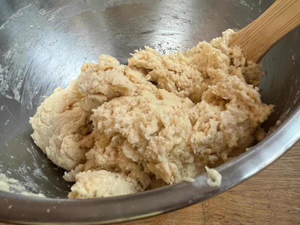 A close-up shot of a dough-like mixture inside a silver mixing bowl.