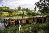 A broken house boat lies surrounded by weeds in the Dal Lake in Srinagar, Indian controlled Kashmir, Saturday, Aug. 28, 2021. Weeds, silt and untreated sewage are increasingly choking the sprawling scenic lake, which dominates the city and draws tens of thousands of tourists each year. (AP Photo/Mukhtar Khan)