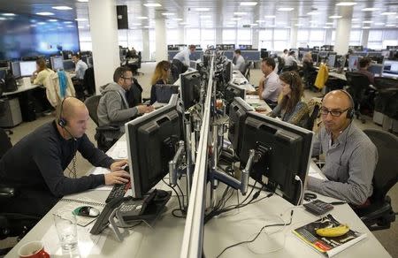 Traders sit at their desks at IG Index in London September 9, 2014. REUTERS/Luke MacGregor/Files