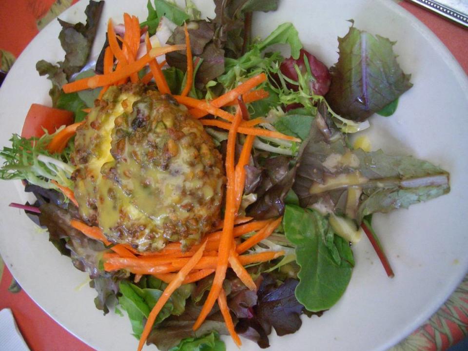 Pistachio-encrusted goat cheese on salad greens drizzled in passionfruit dressing at Perricone’s Marketplace and Cafe.
