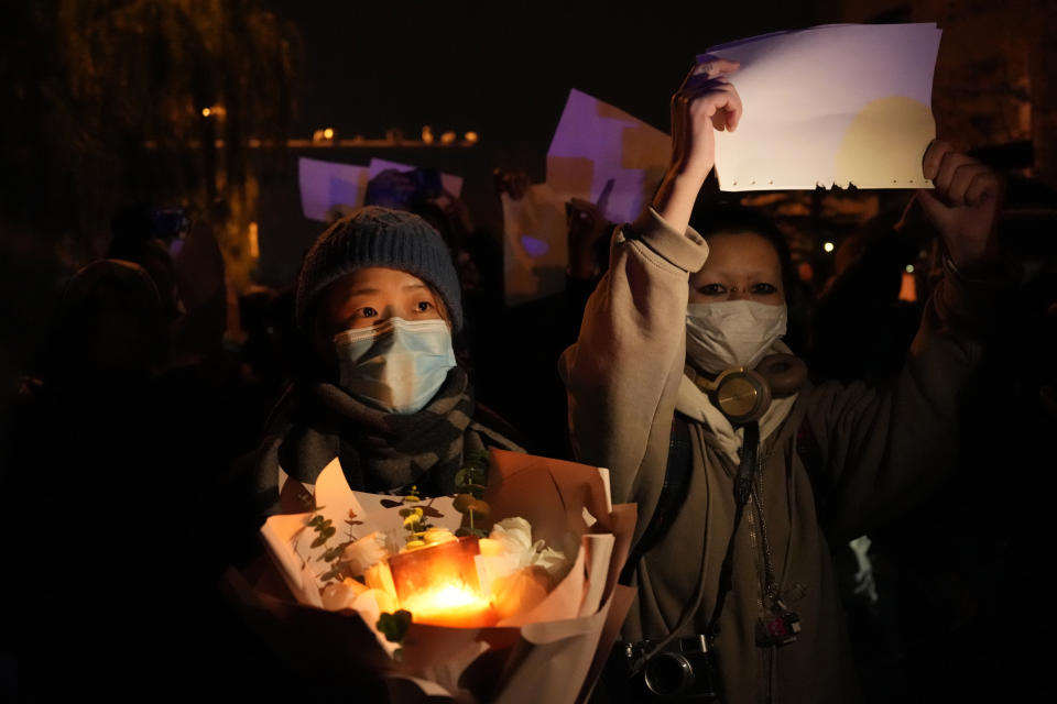 Protesters hold up blank papers and hold flowers and candles as they march in protest in Beijing, Sunday, Nov. 27, 2022. Protesters angered by strict anti-virus measures called for China's powerful leader to resign, an unprecedented rebuke as authorities in at least eight cities struggled to suppress demonstrations Sunday that represent a rare direct challenge to the ruling Communist Party. (AP Photo/Ng Han Guan)