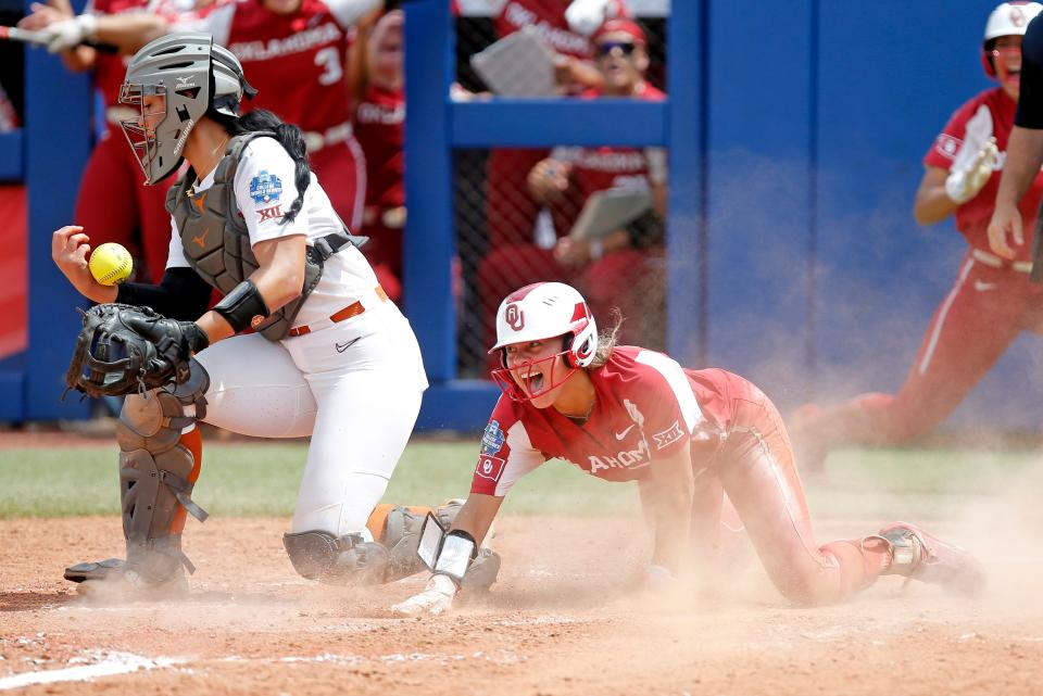 Oklahoma's Jayda Coleman (24) celebrates after scoring at home as Texas' Mary Iakopo tries to hold on to the ball during Saturday's Women's College World Series game.