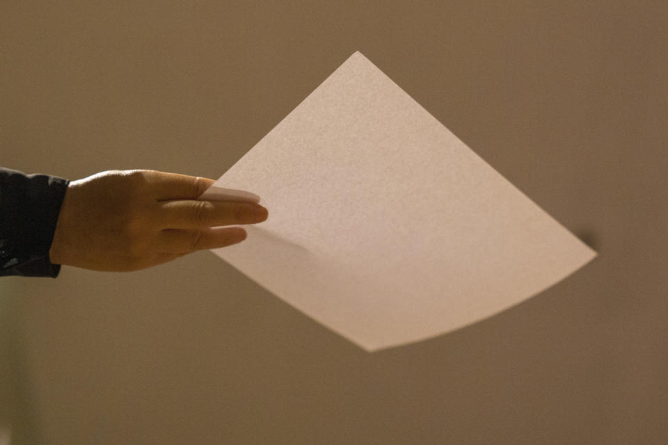 A person holds a piece of white paper during a protest gathering at the University of Hong Kong in Hong Kong, Tuesday, Nov. 29, 2022. On Tuesday, about a dozen people gathered at the University of Hong Kong, chanting against virus restrictions and holding up sheets of paper with critical slogans. Most were from the mainland, which has a separate legal system from the Chinese territory of Hong Kong, and some spectators joined in their chants. (AP Photo/Bertha Wang)