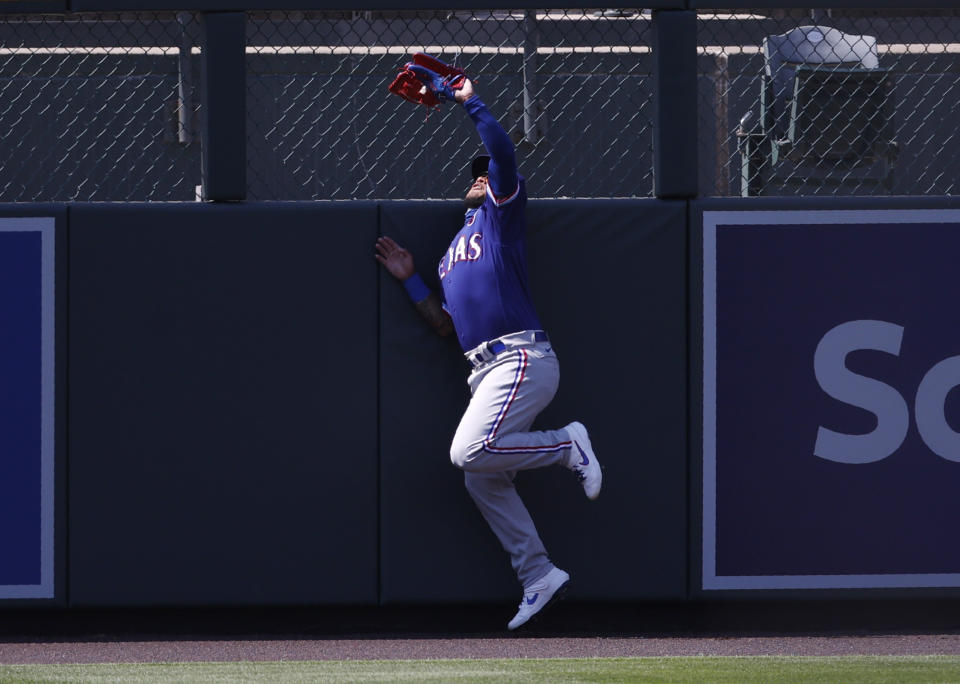 Texas Rangers left fielder Willie Calhoun hits the fence as he pulls in a fly ball off the bat of Colorado Rockies' Nolan Arenado in the sixth inning of a baseball game Sunday, Aug. 16, 2020, in Denver. (AP Photo/David Zalubowski)