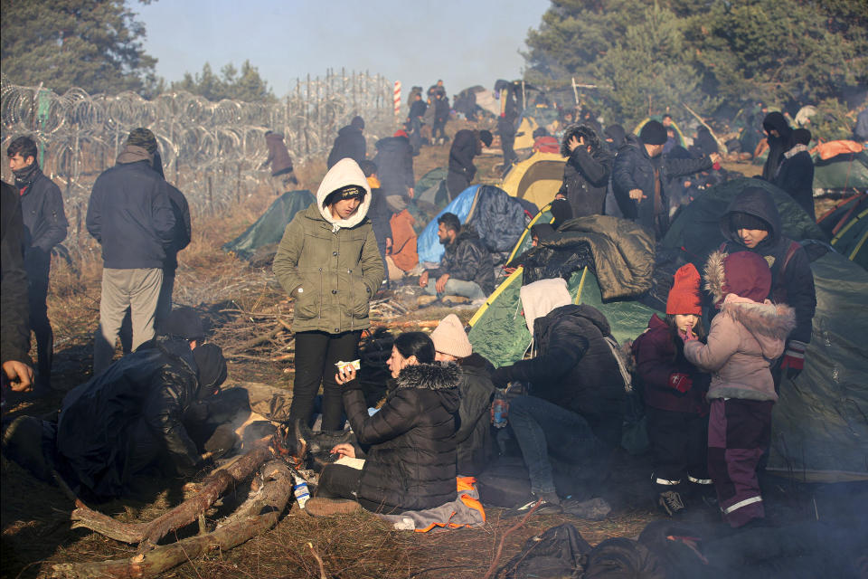 Migrants from the Middle East and elsewhere gather at the Belarus-Poland border near Grodno, Belarus, Tuesday, Nov. 9, 2021. Polish riot police and coils of razor wire faced off Tuesday against migrants, including families with young children, who were camped just across the border in Belarus, amid a tense standoff on the European Union's eastern border. (Leonid Shcheglov/BelTA via AP)