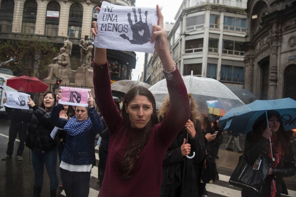 Women protest in the rain in Buenos Aires with "Ni Una Menos" signs.