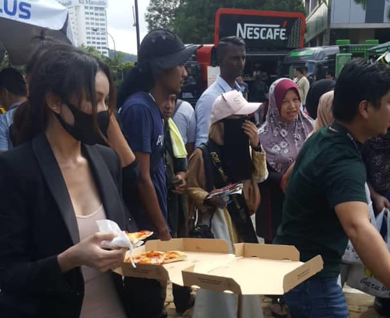 Cleo International CEO Nur Fathiah Syazwana Shaharuddin, better known by her moniker Cleopatra, hands out pizza to members of the media outside Istana Negara February 26, 2020. — Picture by R. Loheswar