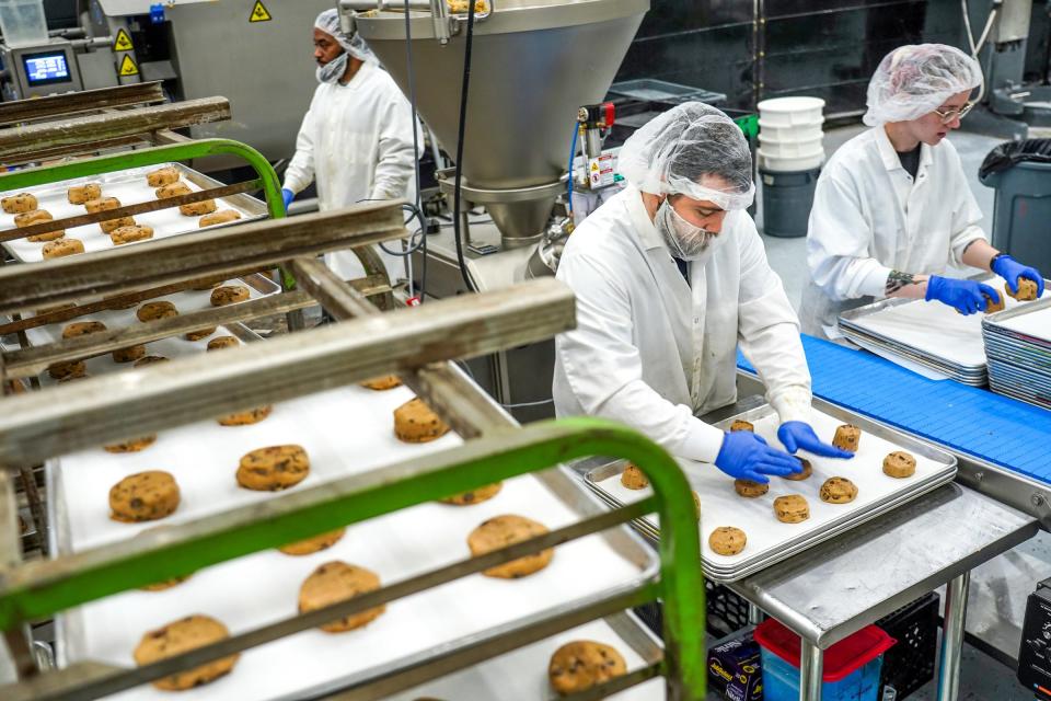 D'VINE Cookies employees Jacob Rich, center, and Molly Stanis, right, work on cutting cookie dough and shaping cookies to be baked at an industrial kitchen space in Taylor on January 4, 2023.