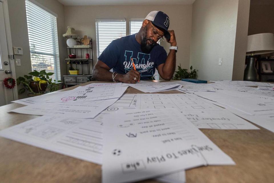 Special Education teacher Quincy Luper grades his students homework assignments at his home in Fort Worth on Wednesday, Dec. 6, 2023. Luper teaches at Willis Lane Elementary School and said he often stays late to finish work and uses his own money to supply his students with what he needs.