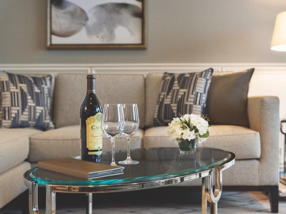 A bottle of wine and empty glasses on a coffee table by a couch.