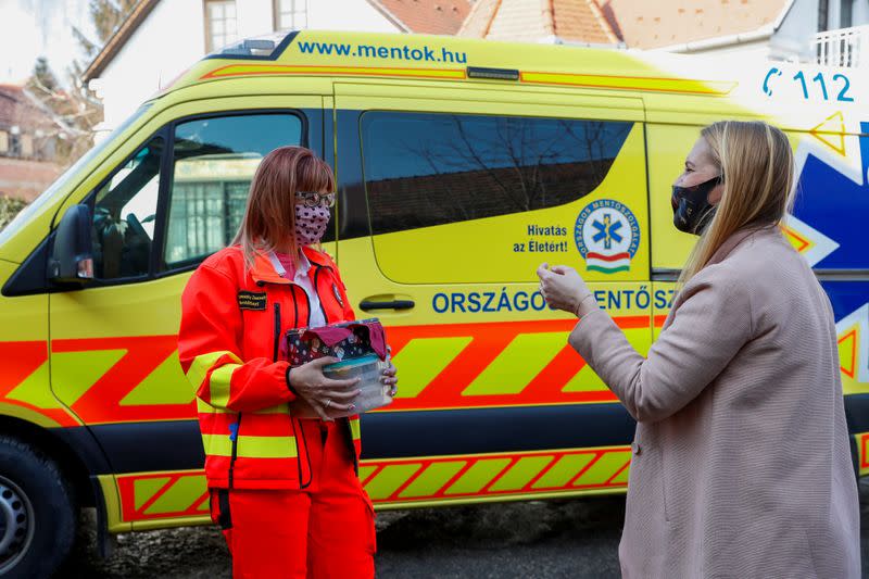 Eszter Harmath talks with a paramedic as she delivers pastries, during COVID-19 pandemic, in Szentendre