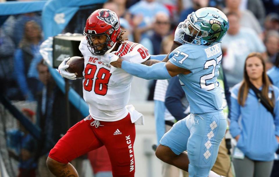 N.C. State wide receiver Devin Carter (88) stiff-arms North Carolina defensive back Giovanni Biggers (27) as he gains yards after a catch during the first half of N.C. State’s game against UNC at Kenan Stadium in Chapel Hill, N.C., Friday, Nov. 25, 2022.