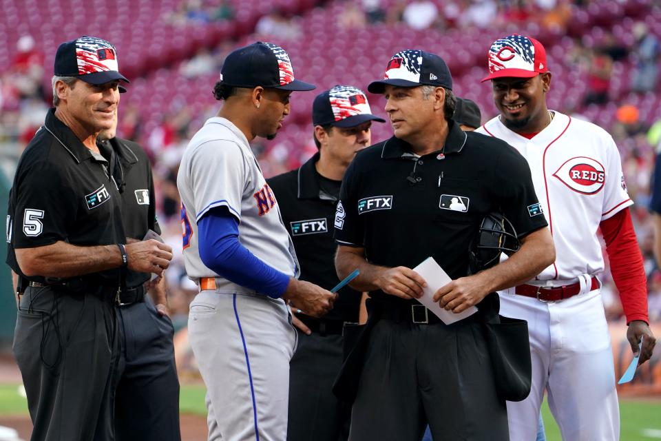 Brothers Edwin Diaz, left, and Alexis Diaz, right, present the lineup cards to the umpires prior to a baseball game between the New York Mets and the Cincinnati Reds, Monday, July 4, 2022, at Great American Ball Park in Cincinnati.