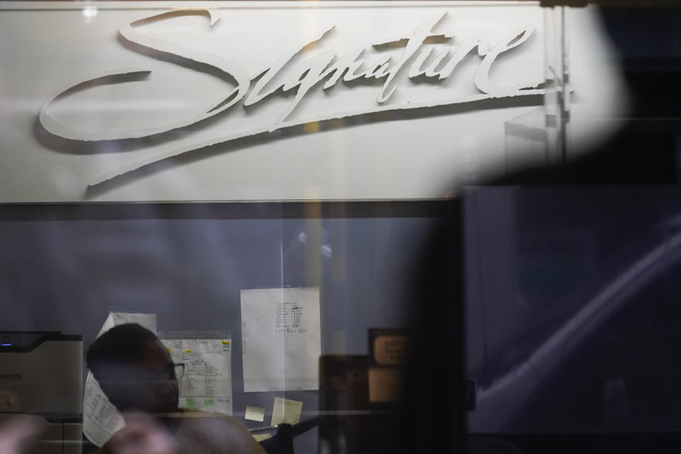 A woman works at a branch of Signature Bank in New York, Monday, March 13, 2023. President Joe Biden is telling Americans that the nation's financial systems are sound. This comes after the swift and stunning collapse of two banks that prompted fears of a broader upheaval. (AP Photo/Seth Wenig)